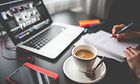 Macbook mit Kaffee, Händen und Schreibblock
